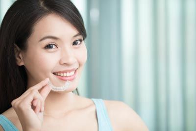 woman holding her Invisalign from Optima Dental