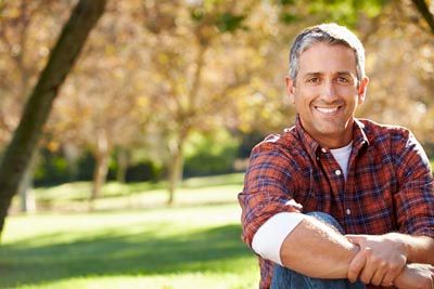 man smiling with his new mini dental implants
